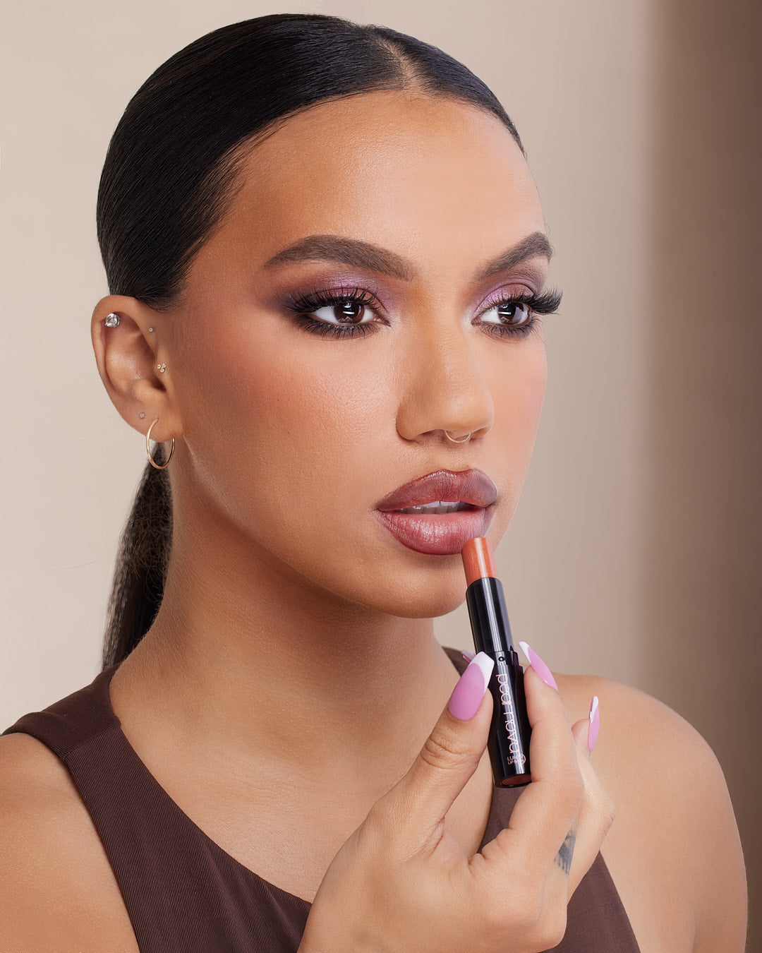 Model headshot holding Orbit Lip Balm applying product to lips