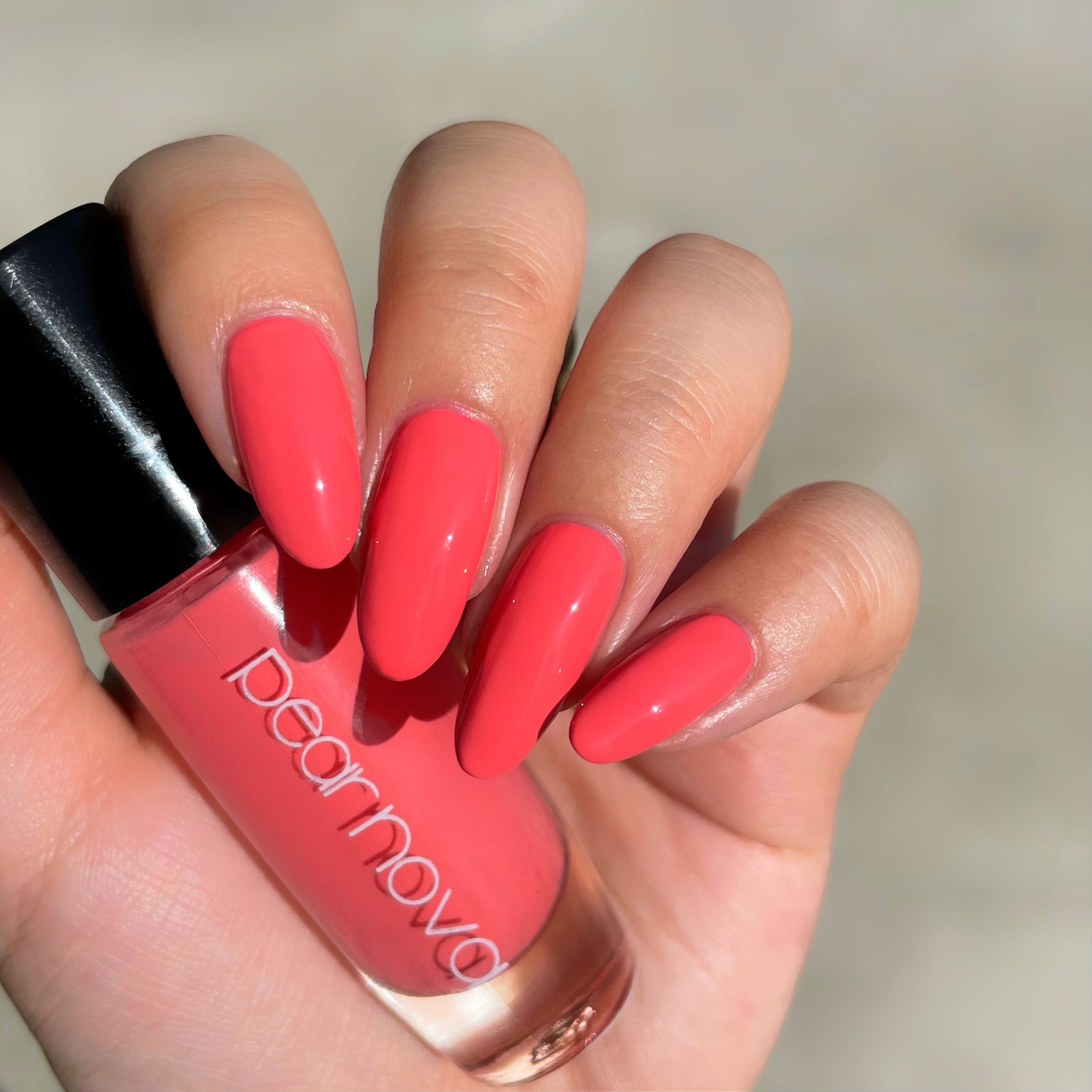 fair skin hand model holding bottle of nail polish with almond shaped nails painted