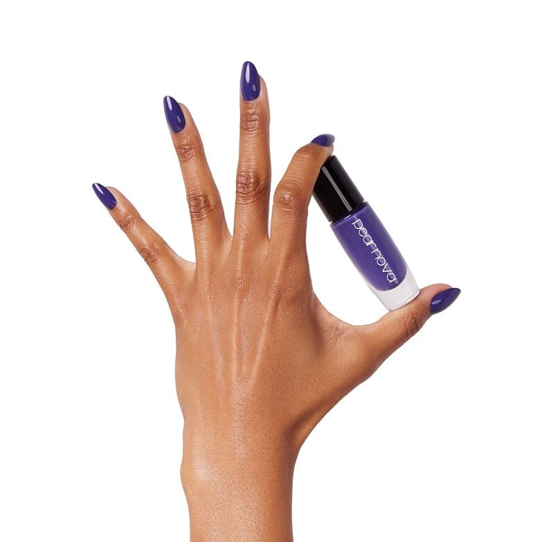 brown skin hand with almond shaped violet nails holding a bottle of Beacoup Bougie Classic Nail Lacquer