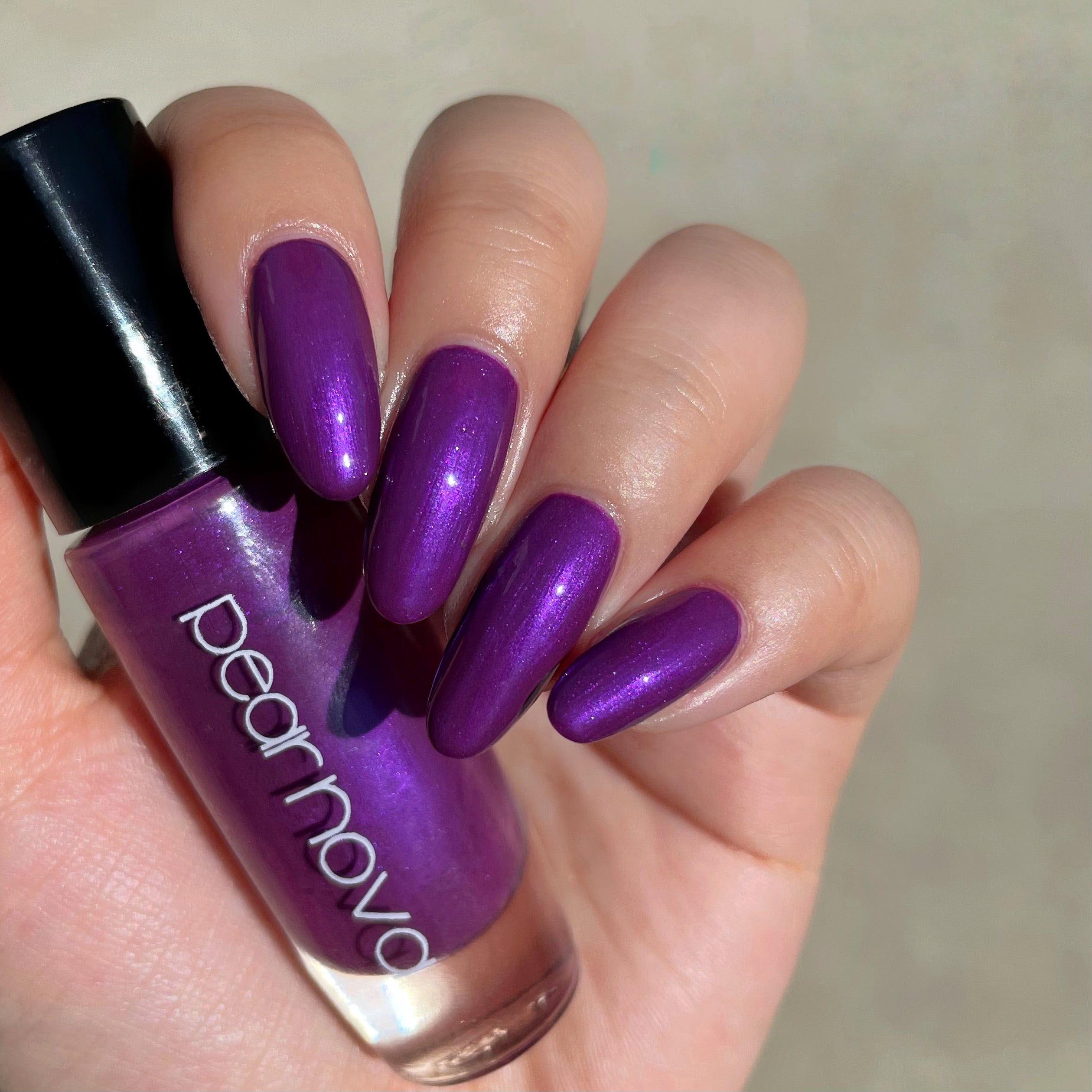 fair skin hand model holding bottle of nail polish with almond shaped nails painted