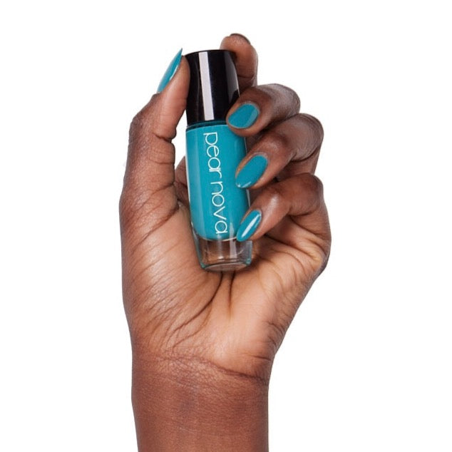 brown skin hand model holding bottle of nail lacquer with turquoise painted nails 