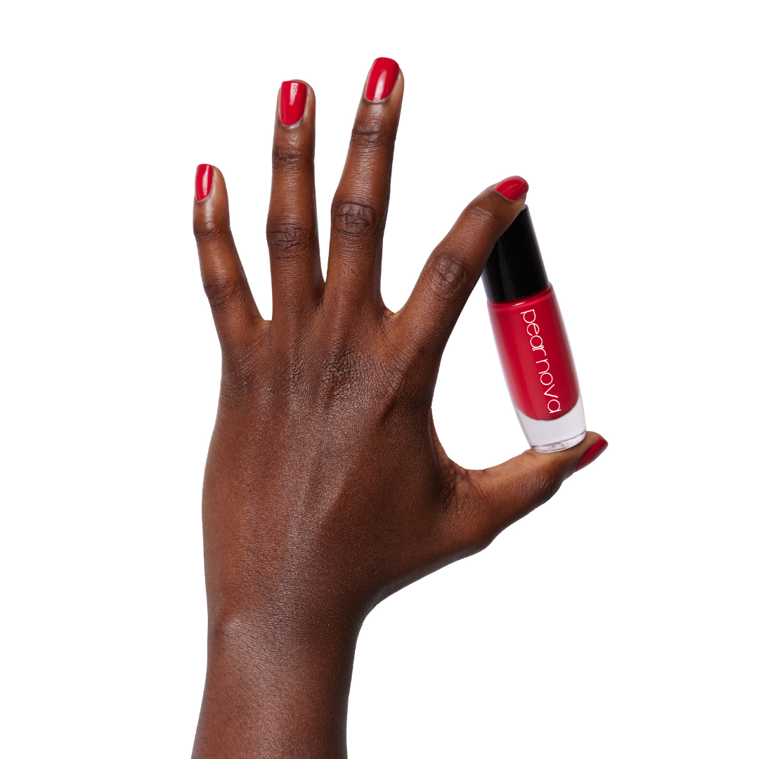 brown skin hand model holding bottle of nail lacquer with red nails in Berry Jane