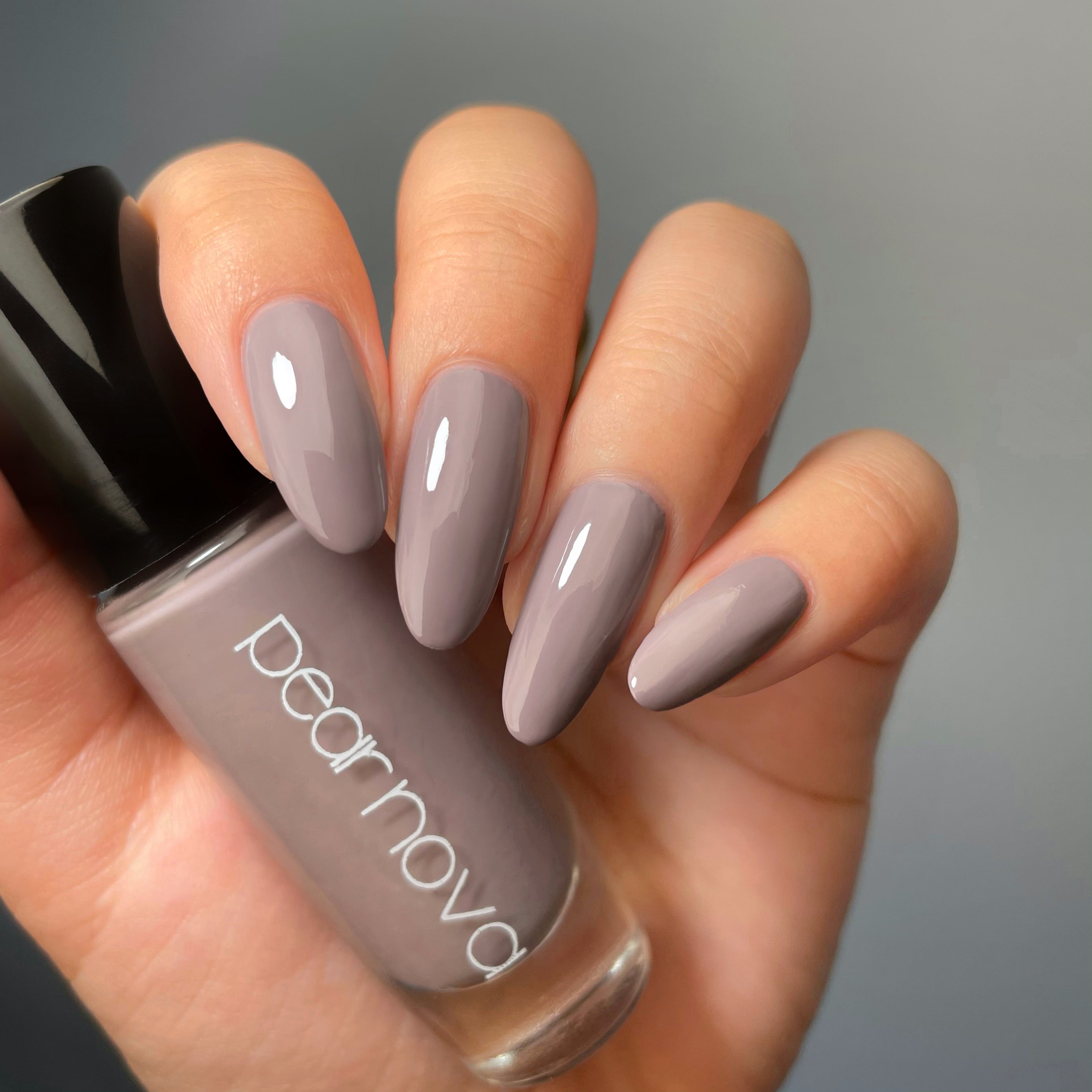 fair skin hand model holding bottle of nail polish with almond shaped nails painted in Ginzaholic 