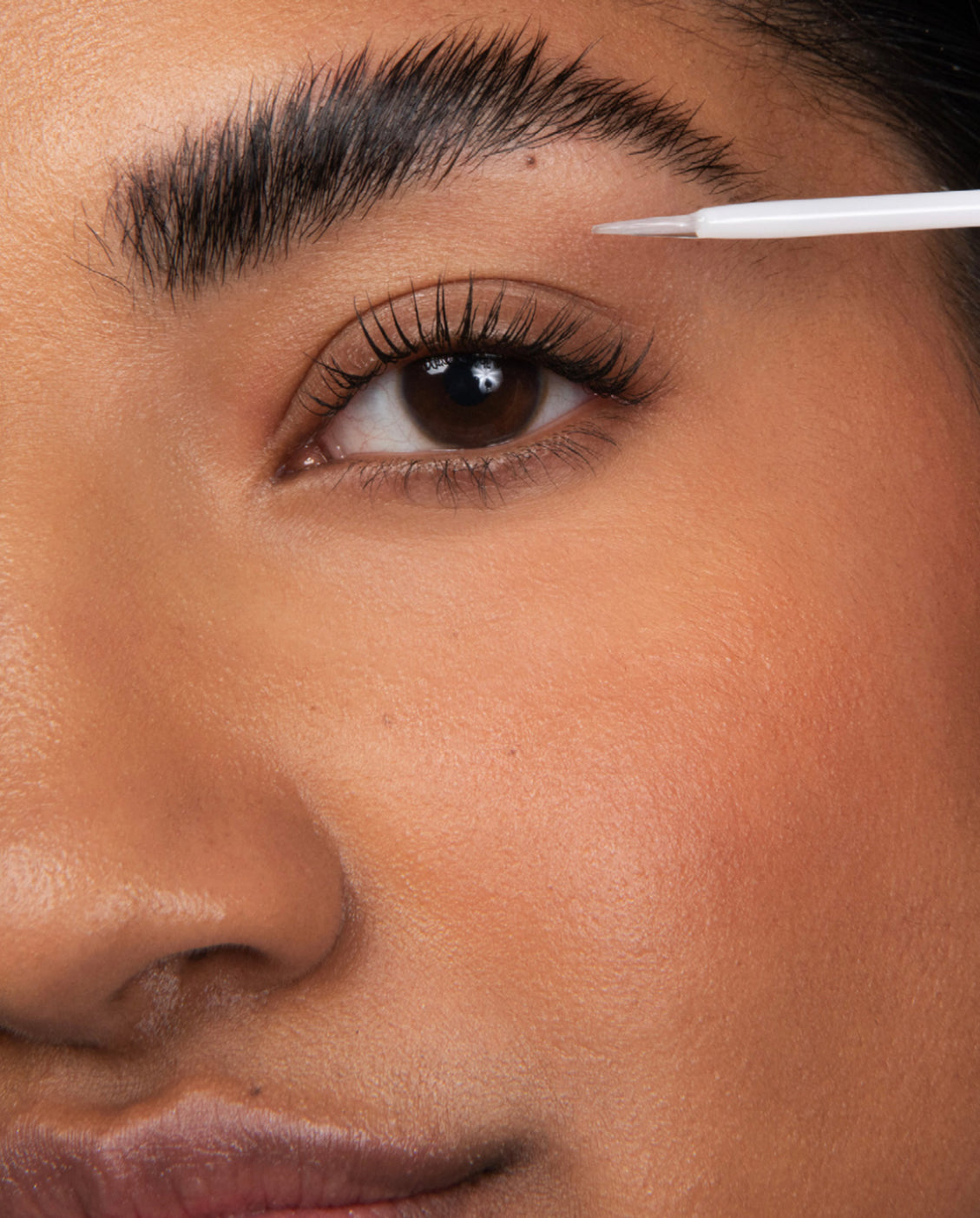 close up of model eye showing long lashes applying lash serum