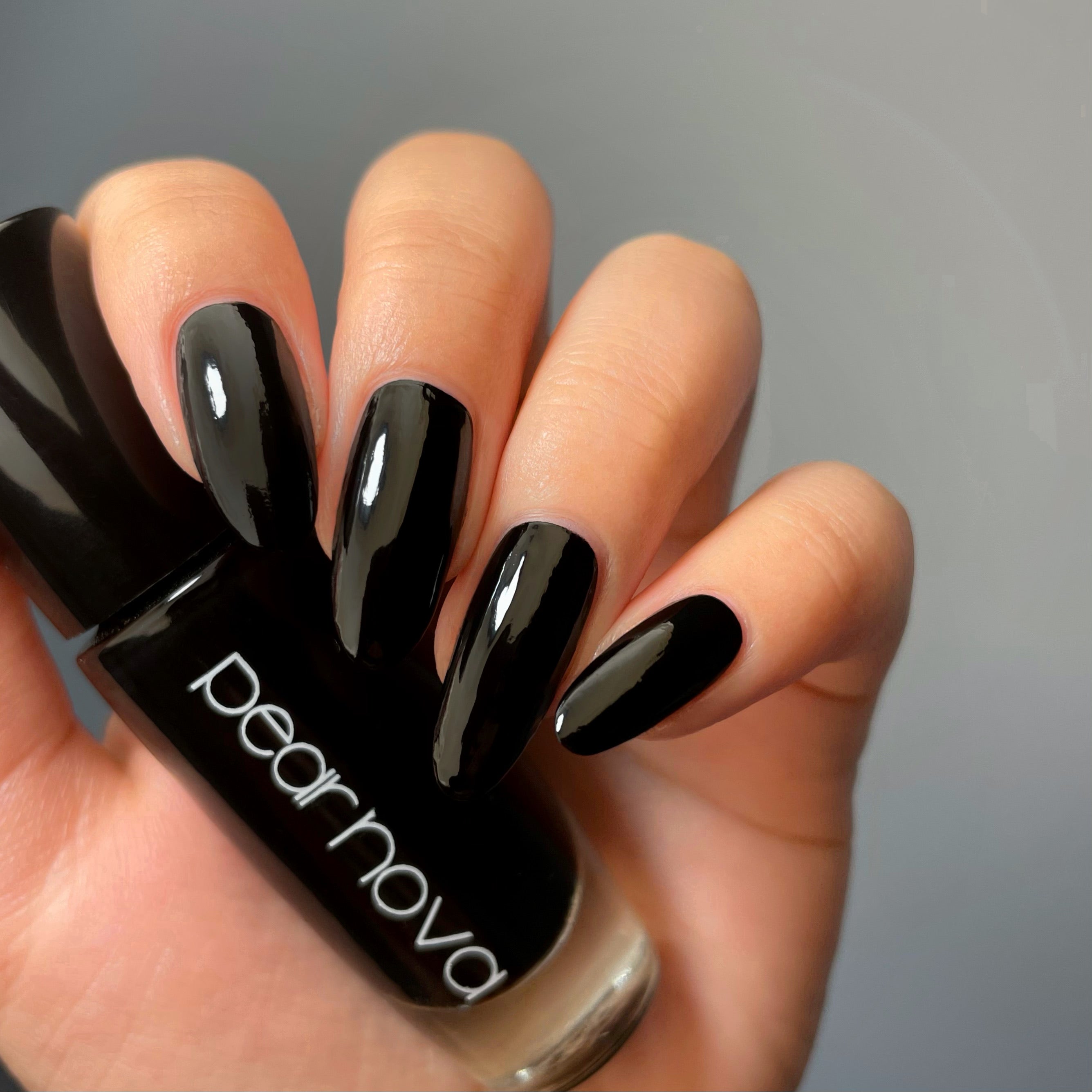 model hand with black nails holding black nail polish
