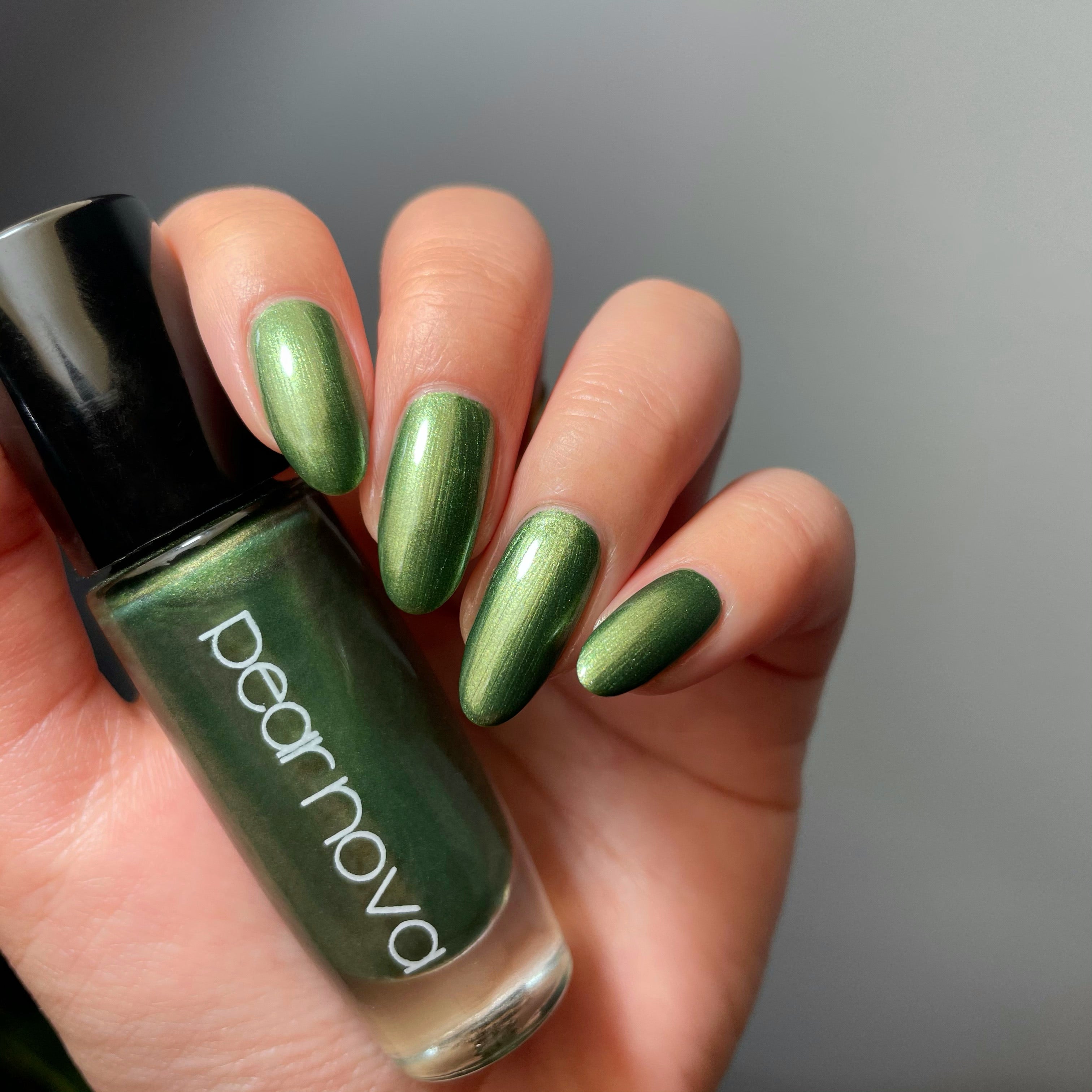 fair skin hand model holding bottle of nail polish with almond shaped nails painted
