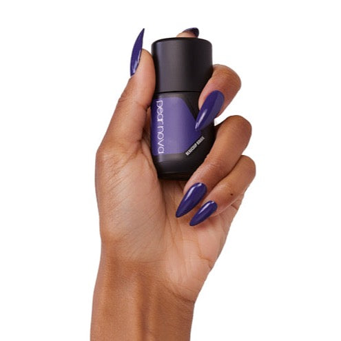 brown skin hand model holding bottle of nail lacquer with almond shaped violet painted nails in Beaucoup Bougie