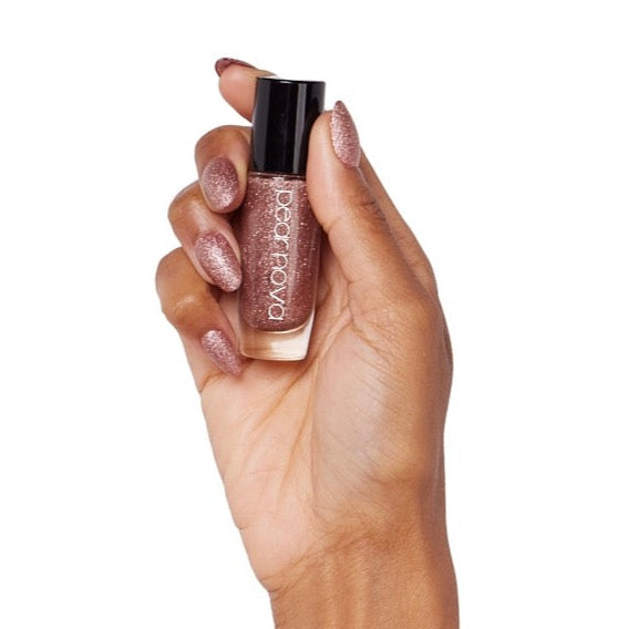 brown skin hand model holding bottle of nail lacquer with almond shaped gold glitter painted nails in Hustle + Glow 